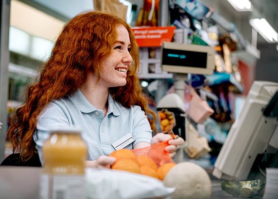 Smiling supermarket checkout worker img text