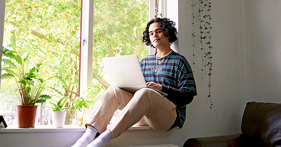 Man using his laptop on window sill