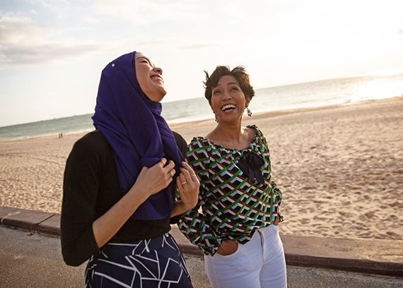 two women walking by the beach smiling