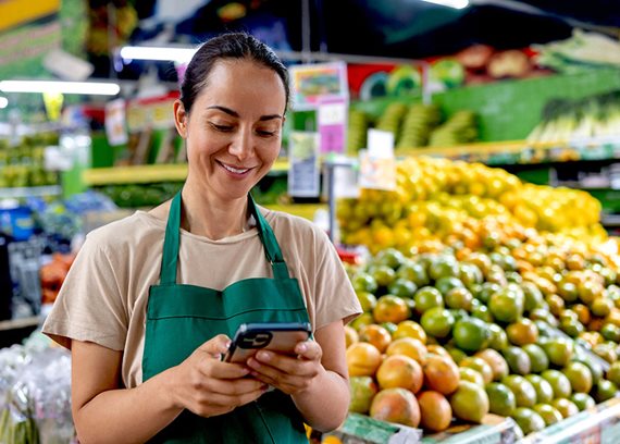 A retail worker smiles as she looks at her phone