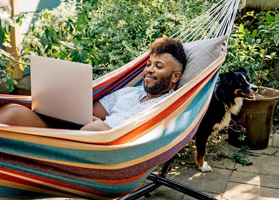 Man in hammock looking at his laptop