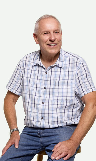 A man smiling, sitting on a bench.