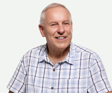 A man smiling, sitting on a bench.