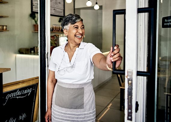 Smiling cafe owner opening the door to the cafe.