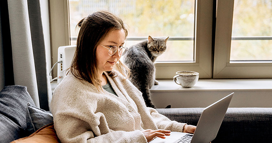 Woman with her cat working from home on a laptop