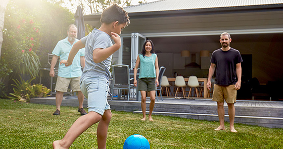 Young family playing soccer in the backyard